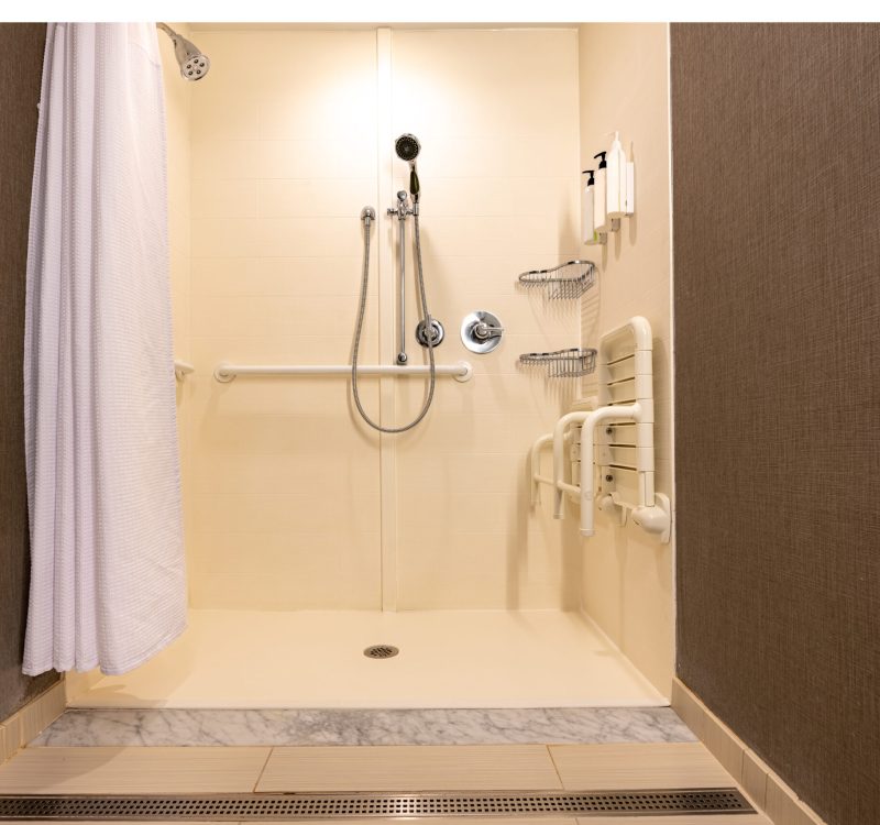 Wheelchair accessible hotel bathroom shower with tile floor and